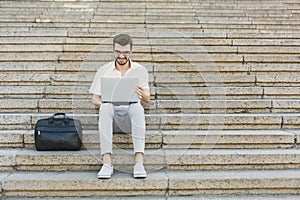 Young businessman working with laptop outdoors