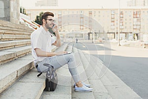 Young businessman working with laptop outdoors