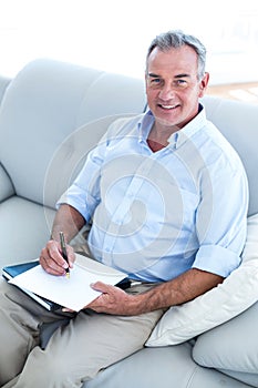 Happy businessman writing on notepad at office