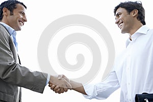 Happy Businessmen Shaking Hands Against Clear Sky