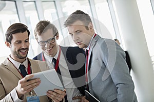 Happy businessmen using digital tablet at convention center