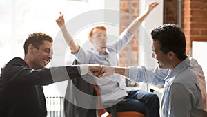 Happy businessmen workers giving fist bump celebrating team project success