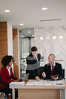 Happy businesspeople while collaborating on a new project in an office. Group of diverse businesspeople using a laptop and tablet