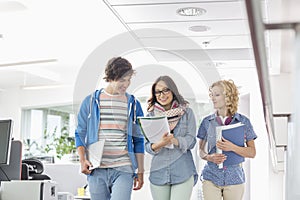 Happy businesspeople discussing while walking in creative office