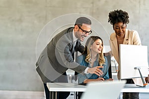 Happy businesspeople laughing while collaborating on a new project in an office.