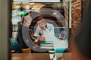 Happy businesspeople smiling cheerfully during a meeting in a coffee shop. Group of successful business professionals