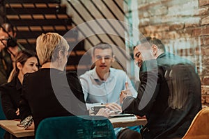 Happy businesspeople smiling cheerfully during a meeting in a coffee shop. Group of successful business professionals