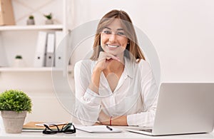 Happy Businessswoman Sitting At Laptop Smiling In Modern Office