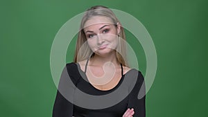 Happy businesswoman in black blouse nodding approvingly to agree into camera at green background.