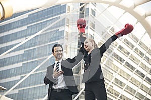 Happy businesswoman with boxing gloves on arms raised in victory