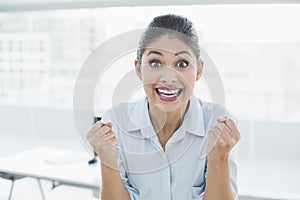 Happy businesswoman clenching fists in office