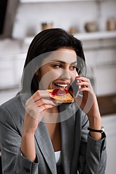 Happy businesswoman eating toast bread with