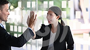 Happy businesswoman giving high five with her colleagues for celebrating successful project.