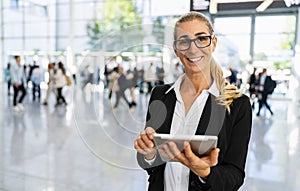 happy businesswoman with glasses at a trade fair holding tablet