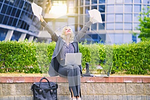 A happy businesswoman with her hands in the air. Woman sitting on a bench in a suit. Concept business, secretary working