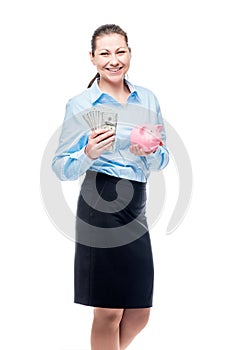 Happy businesswoman holds piggy bank and dollars on white