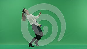 Happy businesswoman listening to music in the headphones and dancing on the spot. She wears formal dress: white shirt