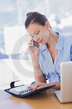 Happy businesswoman looking at her diary and calling