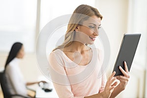 Happy Businesswoman Looking At Touchpad In Office photo