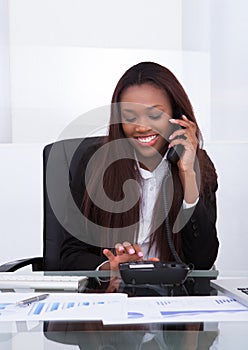 Happy businesswoman making a call from landline photo