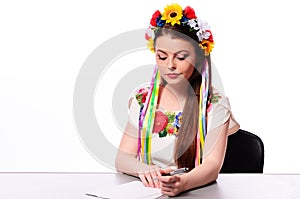 Happy businesswoman with note and pen by a desk.In the Ukrainian national costume