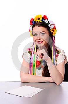 Happy businesswoman with note and pen by a desk.In the Ukrainian national costume