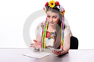 Happy businesswoman with note and pen by a desk.In the Ukrainian national costume
