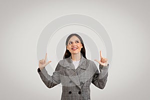 Happy businesswoman pointing upwards at free space and smiling, wearing checkered blazer