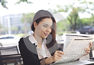 Happy businesswoman reading newspaper and smile