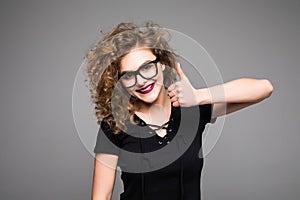 Happy businesswoman showing thumb up over gray background. Looking at camera