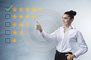 Happy businesswoman showing thumbs up to 5 star rating on concrete wall background. Customer service and excellent feedback