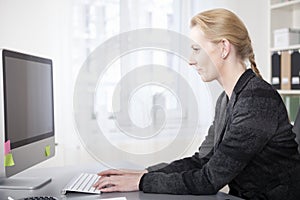 Happy Businesswoman in Side View Tying on Computer