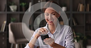 Happy businesswoman sit at workplace smiling using smartphone