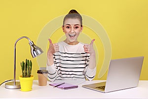 Happy businesswoman sitting office workplace, showing thumbs up, like gesture.