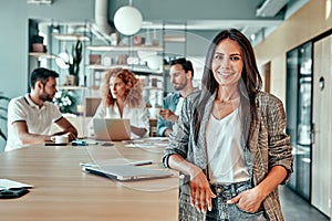 Happy businesswoman standing in modern office and smiling at camera