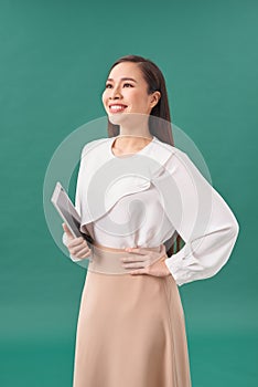 Happy businesswoman standing with table computer over green background