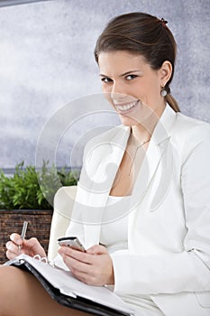 Happy businesswoman taking notes