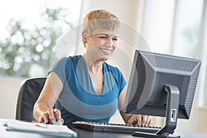 Happy Businesswoman Using Computer At Desk