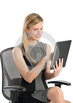 Happy Businesswoman Using Digital Tablet While Sitting On Chair