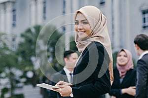 Happy businesswoman wearing black suit  standing  and holding tablet