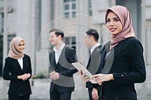 Happy businesswoman wearing black suit standing and holding tablet