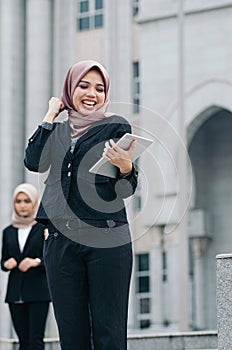 Happy businesswoman wearing black suit  standing  and holding tablet