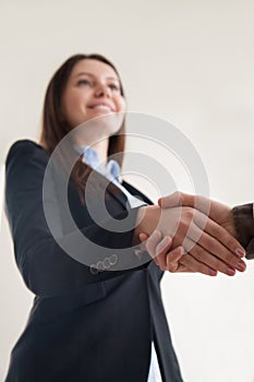 Happy businesswoman wearing suit shaking male hand, focus on han