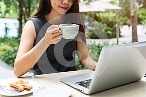 Happy businesswoman working on laptop computer and drinking coffee while sitting in the cafe. Work from anywhere, business and