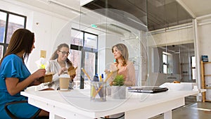 Happy businesswomen eating take out food at office