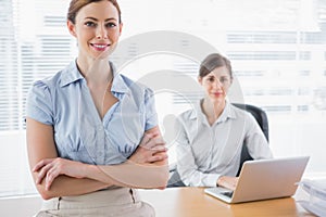 Happy businesswomen smiling at camera at their desk