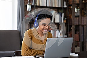 Happy busy African female employee in headphones talking to client