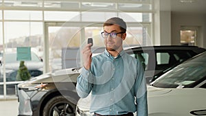 Happy buyer holds new car keys, dealership and sales concept