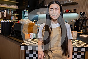 Happy cafe worker posing for the camera in her workplace