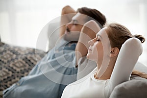 Happy calm couple enjoying relaxation having nap on sofa breathing